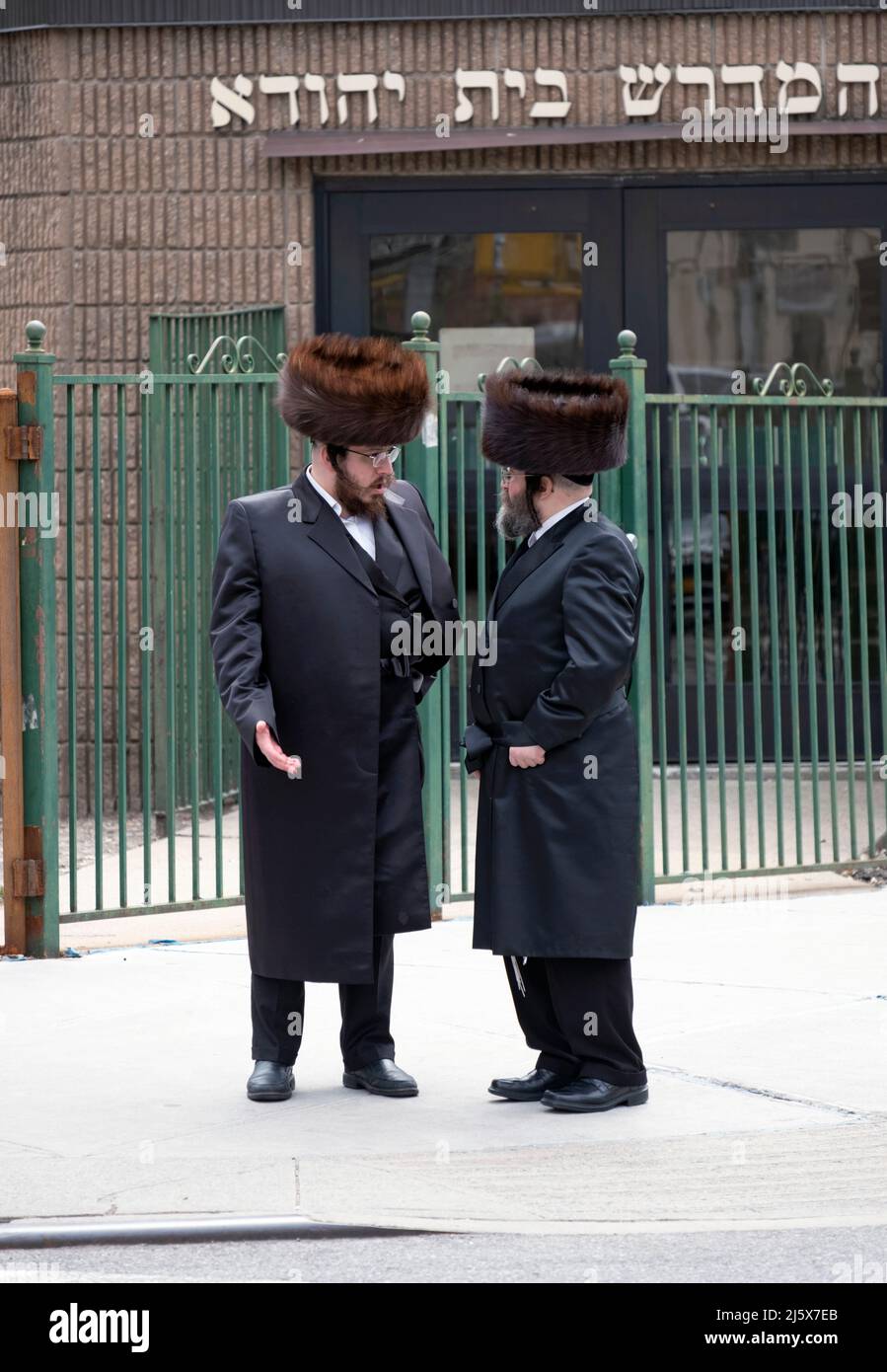 Während des Passahfestes unterhalten sich chassidische jüdische Männer mit Shtreimel-Pelzmützen vor einer Synagoge auf der Bedford Ave. In Williamsburg, Brooklyn, N Stockfoto