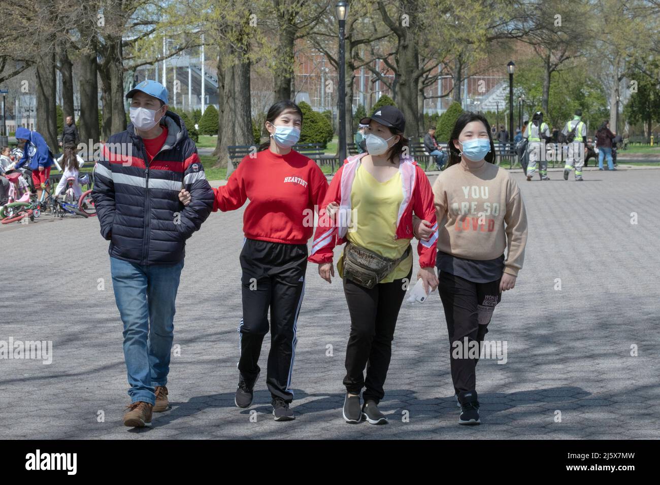 Vier asiatische Amerikaner gehen Arm in Arm um Unisphere herum. Im Flushing Meadows Corona Park an einem milden Frühlingstag Stockfoto
