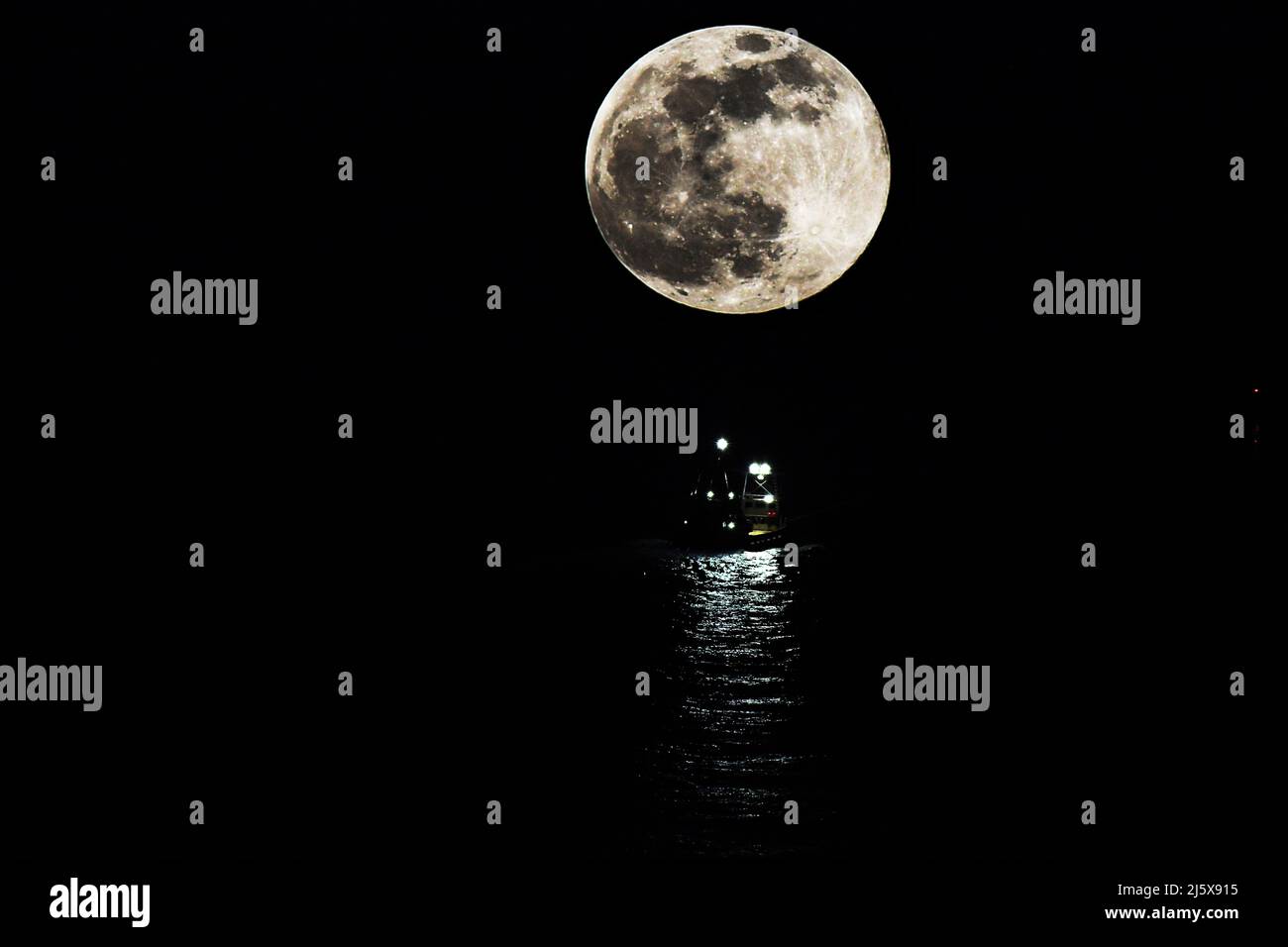 MONDSCHEINSTRÖMUNG: Der Mond steigt direkt über einem Schlepper als Leitlicht in den späten Nachtstunden im Atlantik herab. Stockfoto