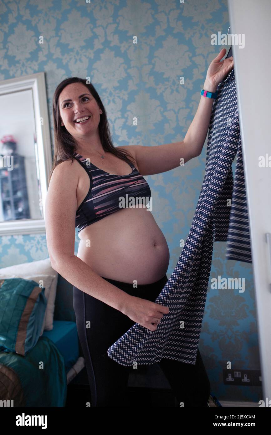 Lächelnde, schwanger Frau, die sich im Schlafzimmer anzieht Stockfoto