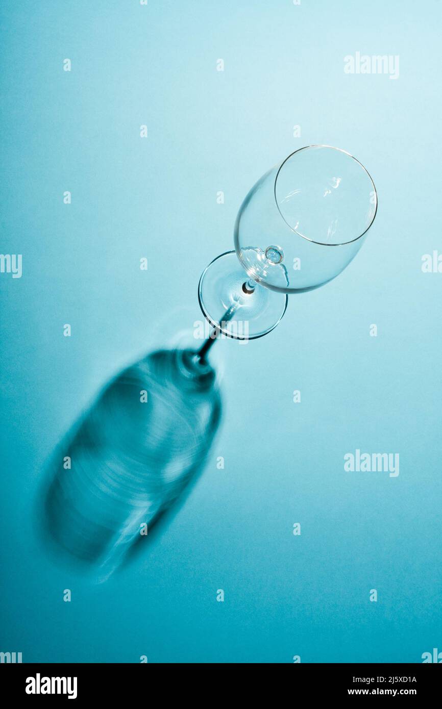 Leeres Weinglas mit einem kreativen Schatten auf blauem Hintergrund. Stockfoto