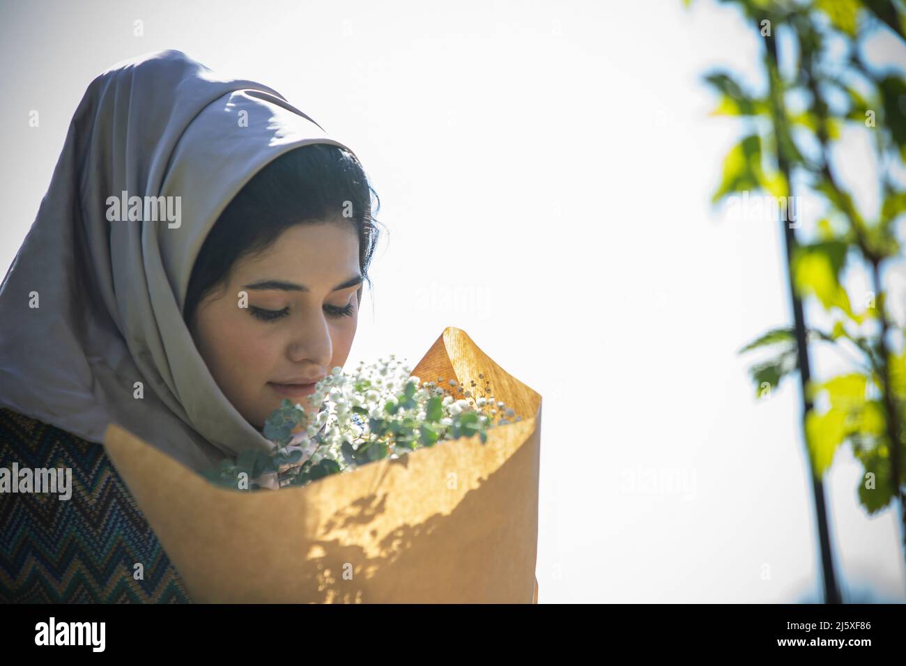 Junge muslimische Frau im hijab riechenden Blumenstrauß Stockfoto