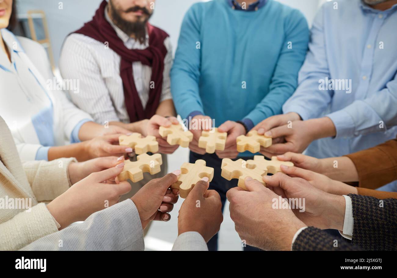 Ein vielfältiges Team von Geschäftsleuten, das Puzzleteile als Metapher für Teamarbeit zusammenfügt Stockfoto