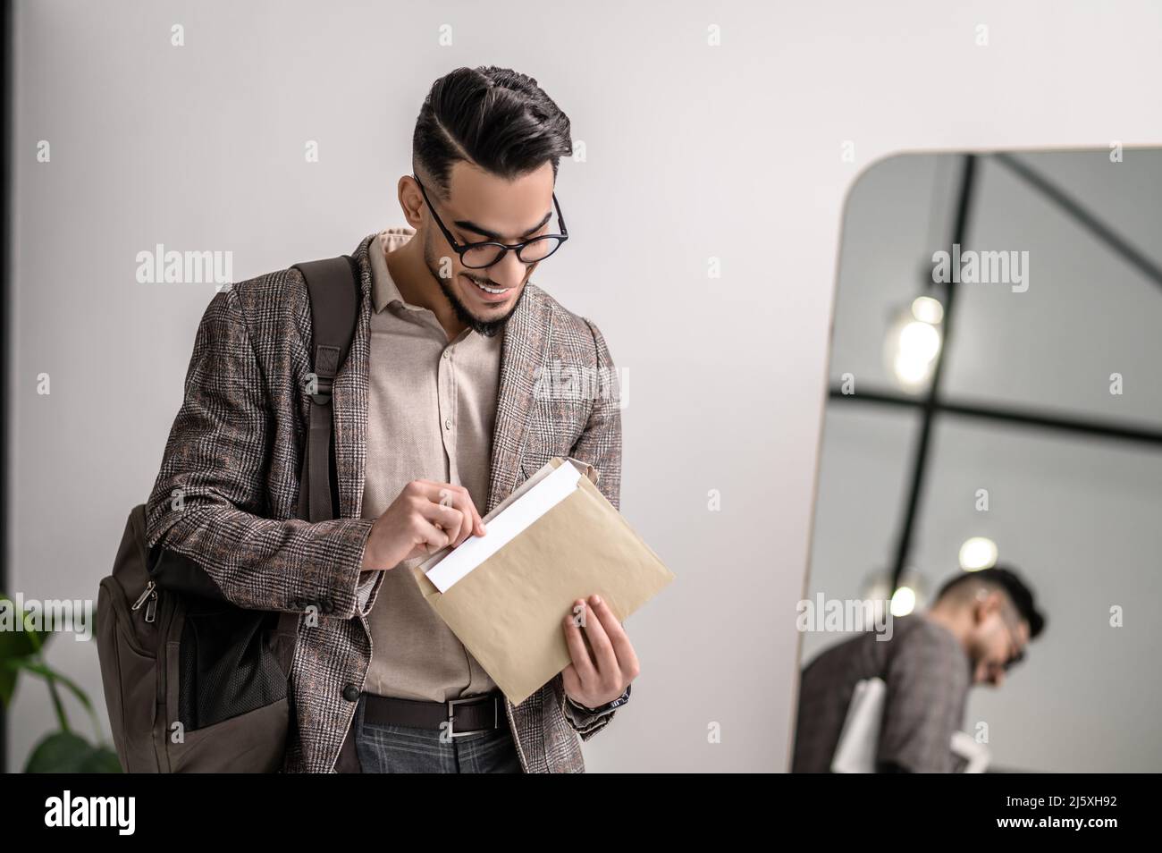Ein junger Mann in stilvoller Jacke, der Papiere liest Stockfoto