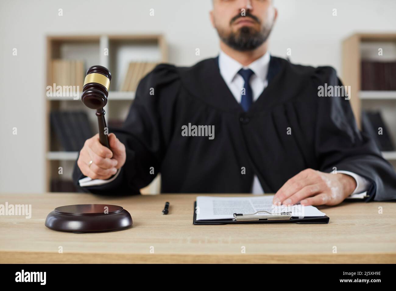 Männlicher Richter, der das Urteil erlässt und die Schließung des Falles ankündigt, indem er Gavel auf den Schallblock trifft. Stockfoto