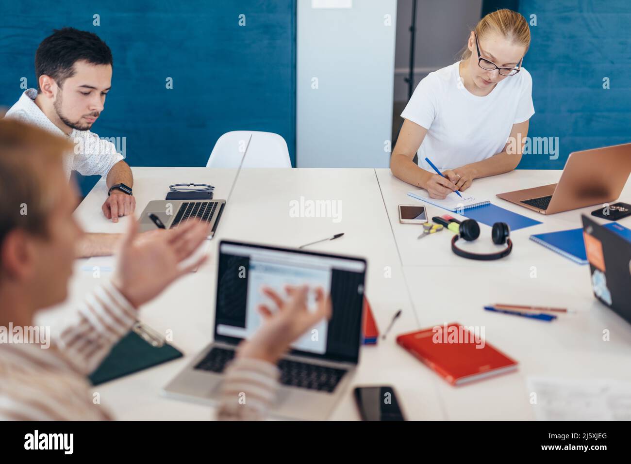 Mitarbeiter kommunizieren bei der Arbeit, indem sie an einem gemeinsamen Tisch sitzen. Stockfoto