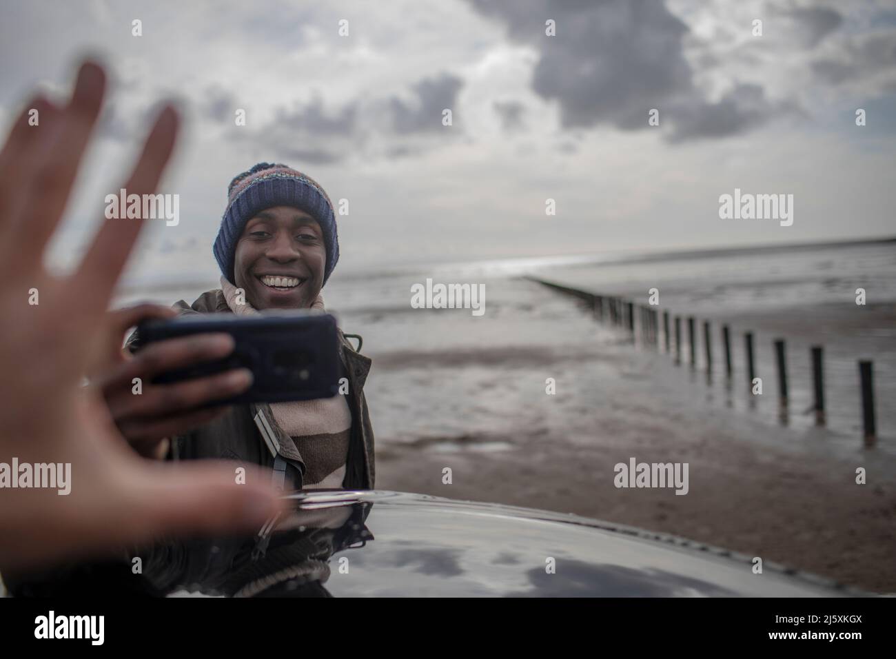 Glücklicher Mann mit Kameratelefon am Winterstrand Stockfoto