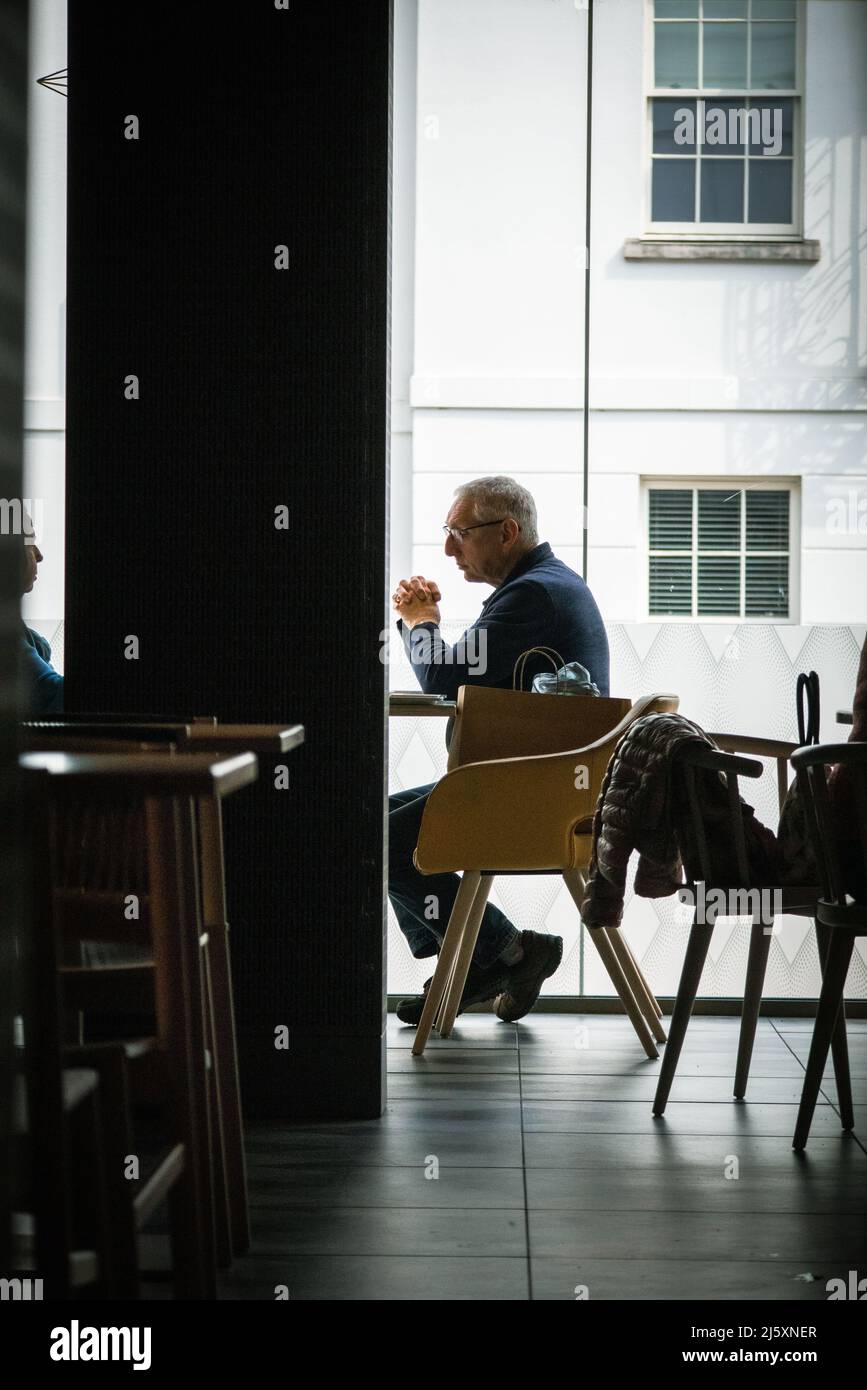 Nachdenklicher, einsamer Mann mittleren Alters, der sich in einem Café entspannt Stockfoto