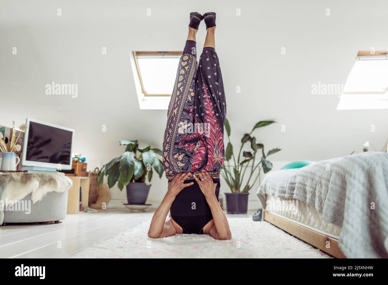 Frau tut Yoga Schulter Stand auf Schlafzimmer Boden Stockfoto