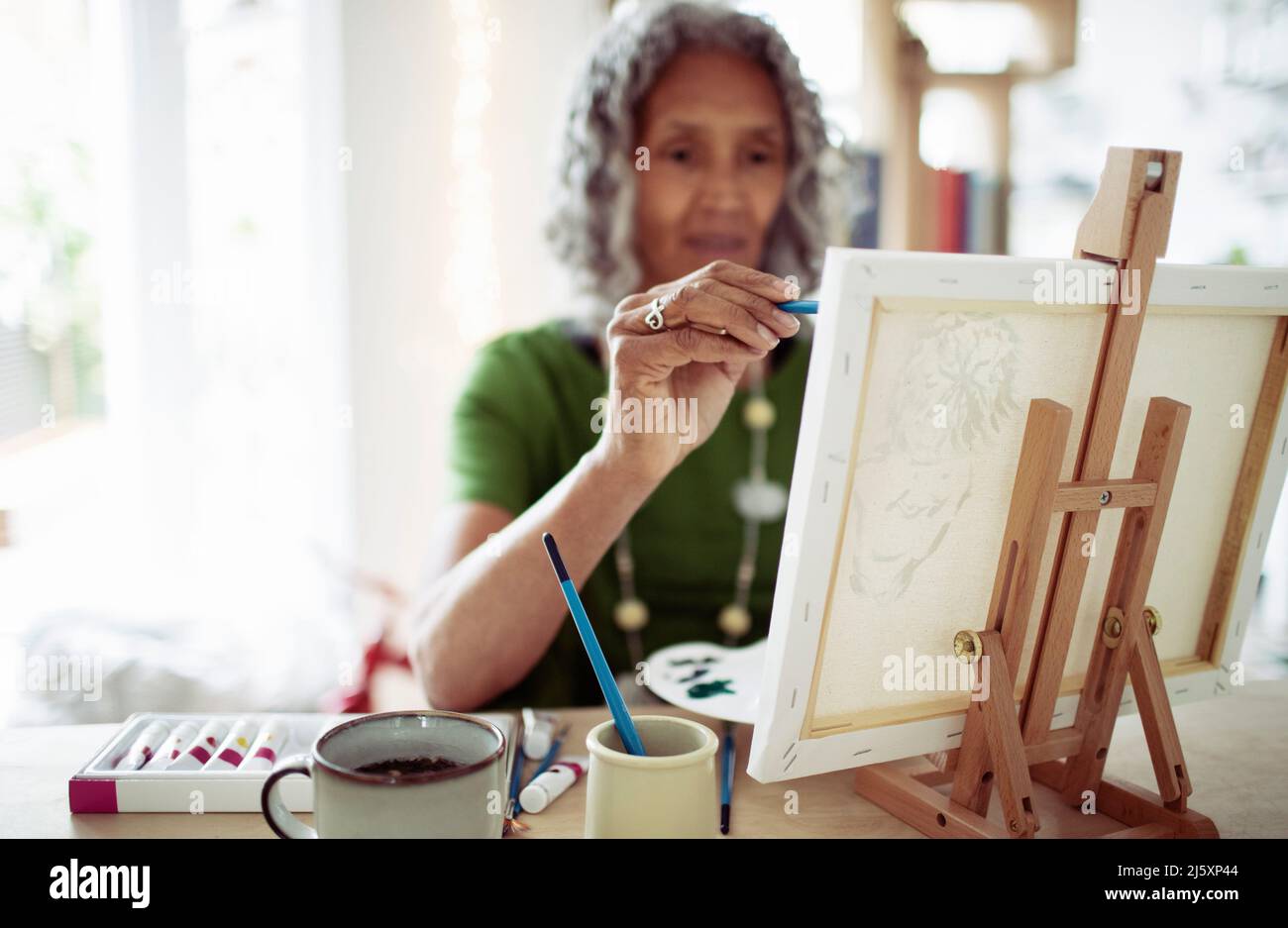 Ältere Frau malt an kleiner Staffelei Stockfoto
