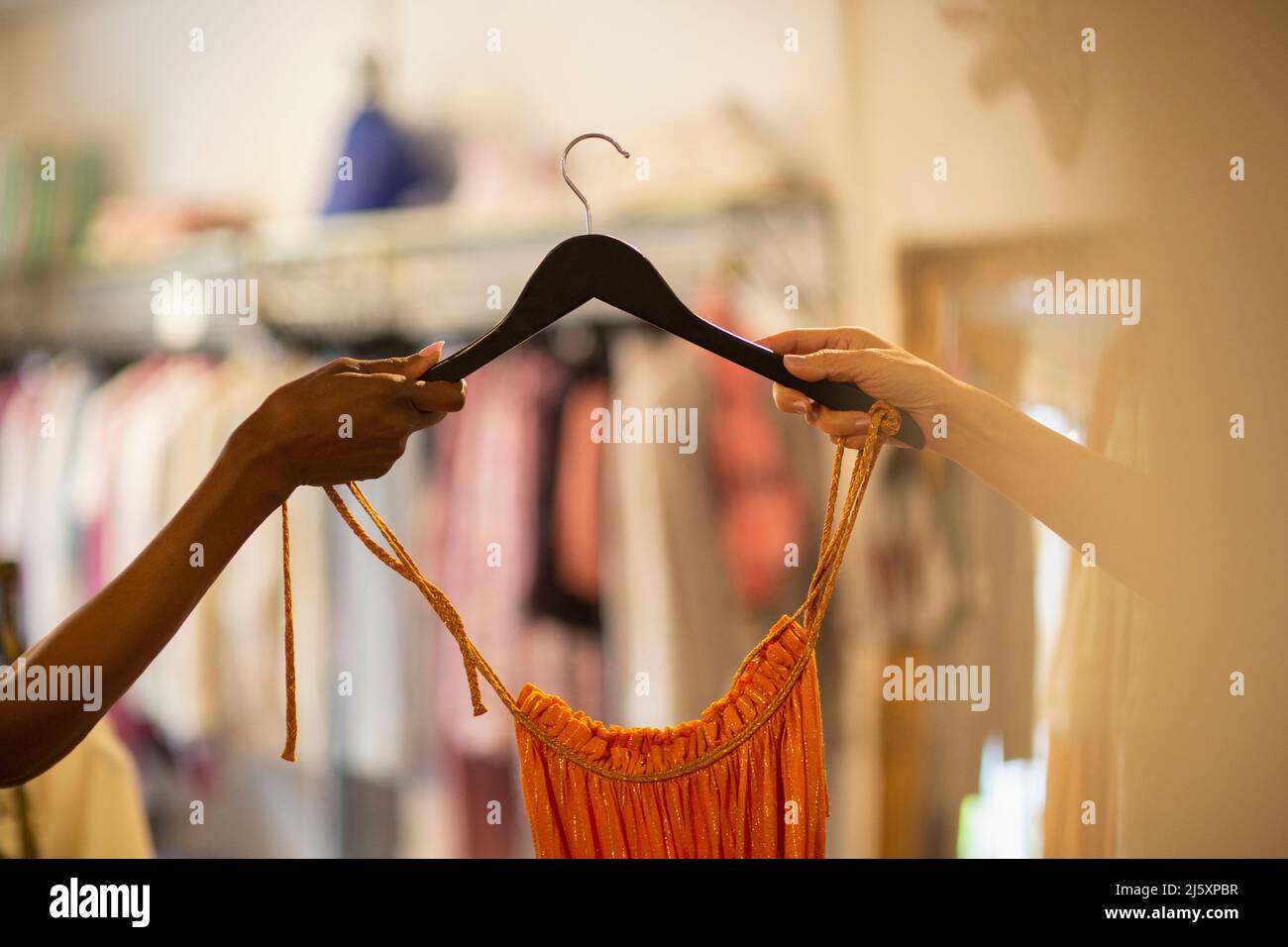 Frau, die dem Kunden im Geschäft Kleidung am Kleiderbügel überreicht Stockfoto
