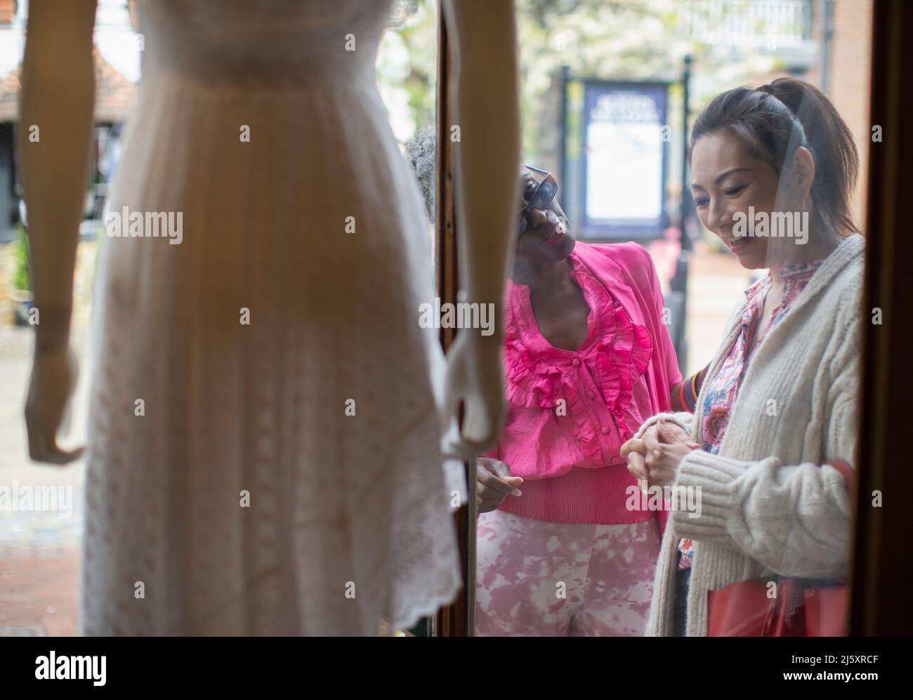 Frauen, Freundinnen, Schaufensterbummel vor der Kleiderboutique Stockfoto