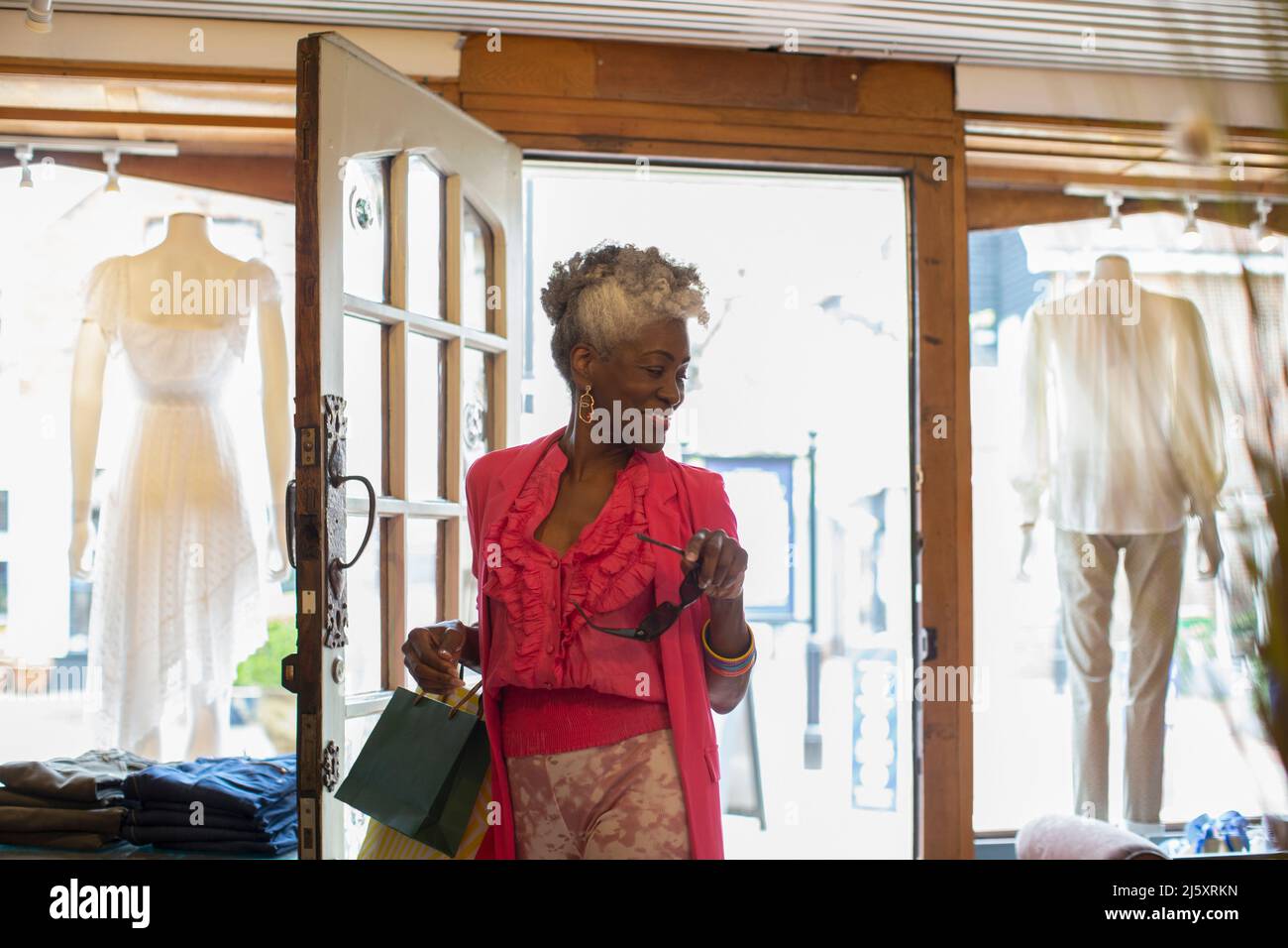 Lächelnde ältere Frau beim Betreten der Bekleidungsboutique Stockfoto