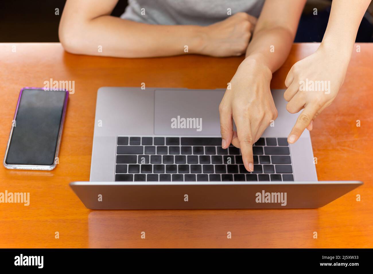 Draufsicht auf die Teamarbeit einer Frau, die die Hand auf den Laptop-Bildschirm zeigt. Stockfoto