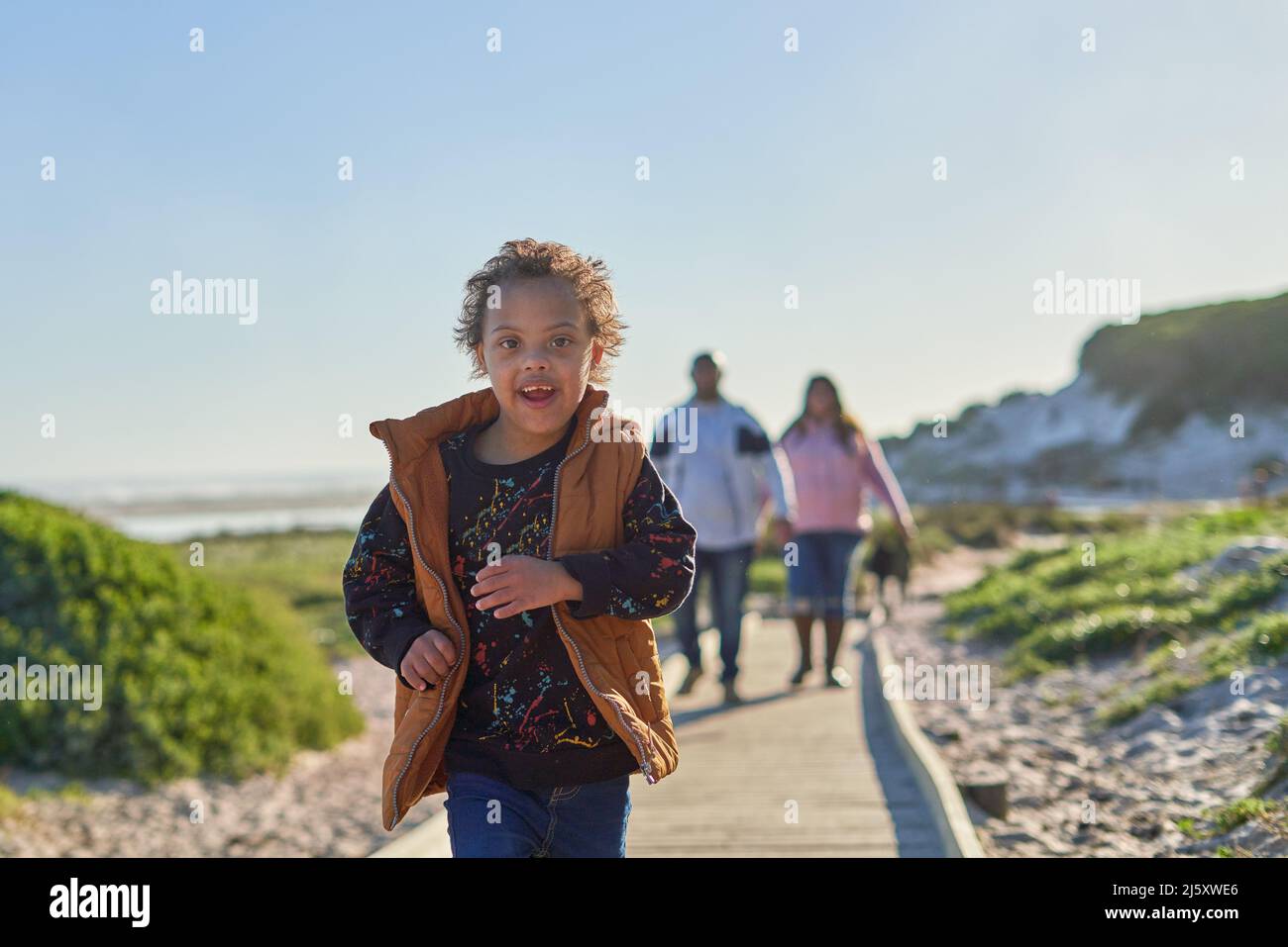 Portrait sorgloser Junge mit Down-Syndrom läuft auf der Strandpromenade Stockfoto
