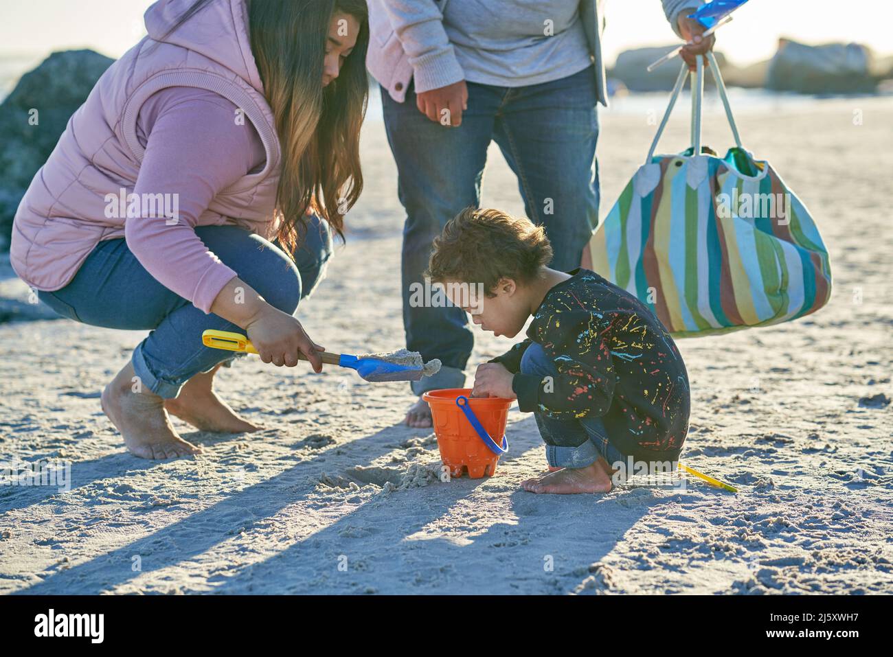 Mutter und Sohn spielen im Sand am sonnigen Strand Stockfoto