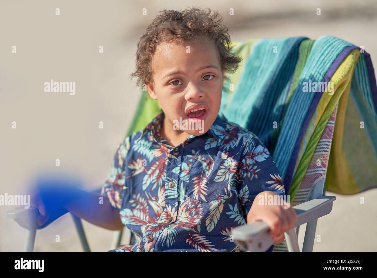 Portrait Junge mit Down-Syndrom im Strandstuhl Stockfoto