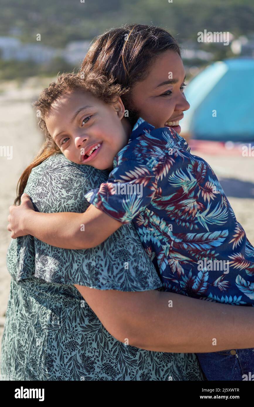 Portrait glücklicher Junge mit Down-Syndrom auf der Schulter der Mutter Stockfoto