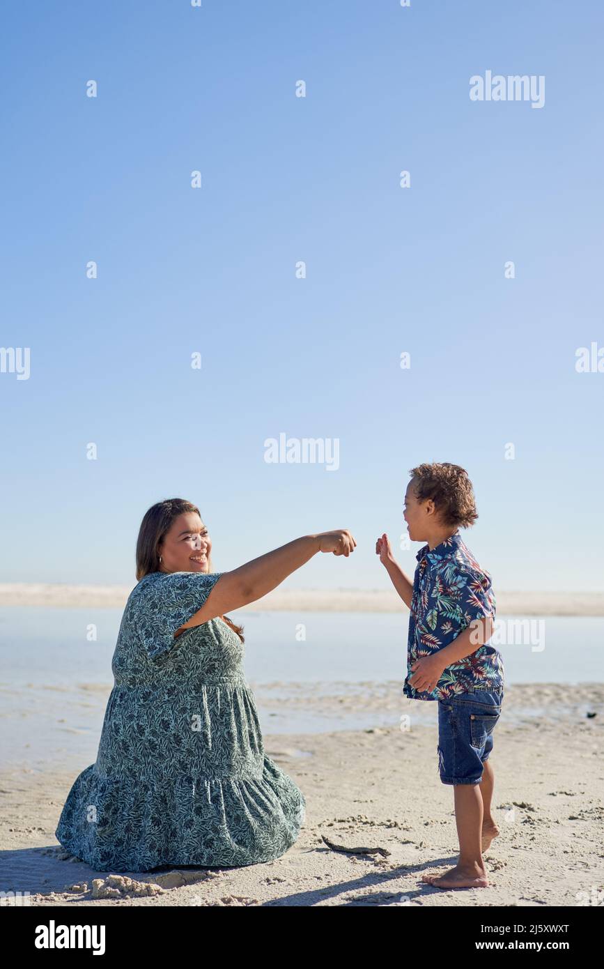 Mutter und Sohn stoßen mit der Faust am sonnigen Strand Stockfoto