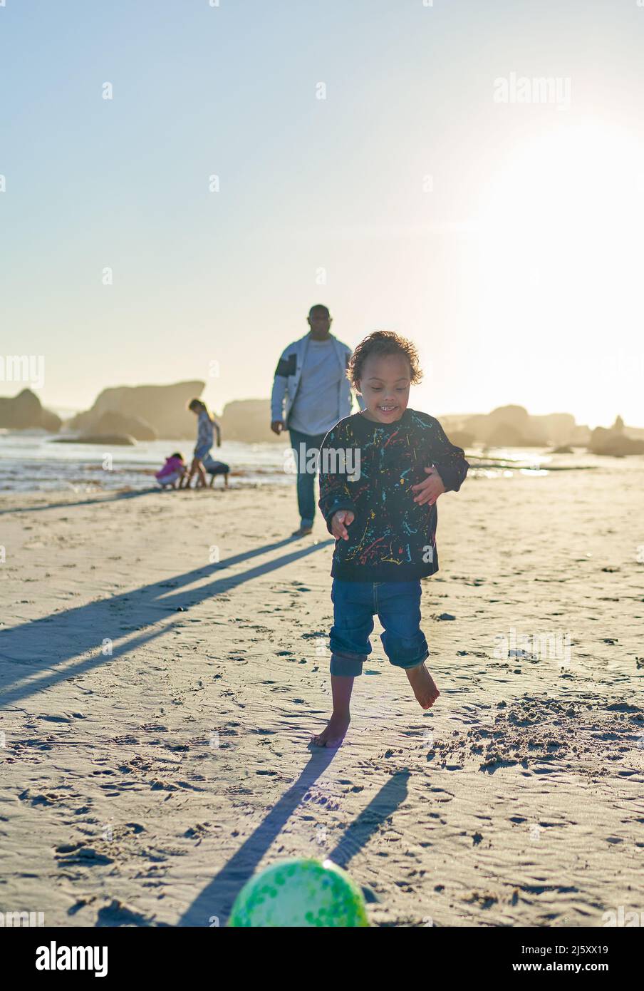 Sorgloser Junge mit Down-Syndrom, der am sonnigen Strand spielt Stockfoto