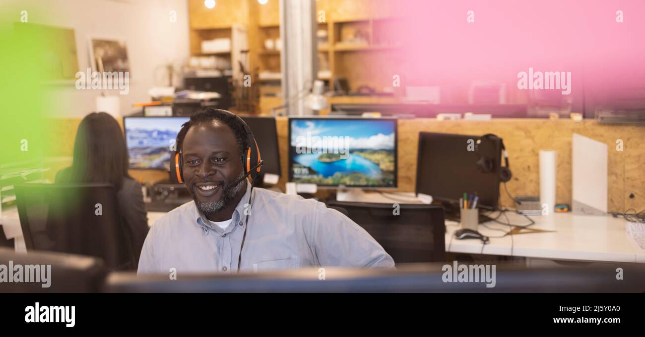 Lächelnder Geschäftsmann mit Headset, der im Büro arbeitet Stockfoto