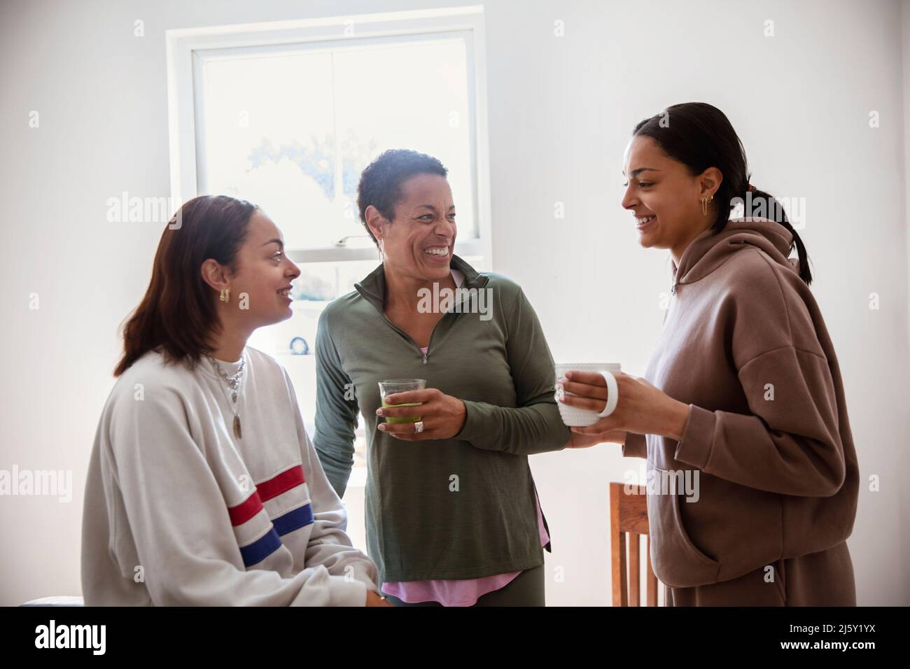 Glückliche Mutter und junge Erwachsene Töchter, die Tee trinken und reden Stockfoto