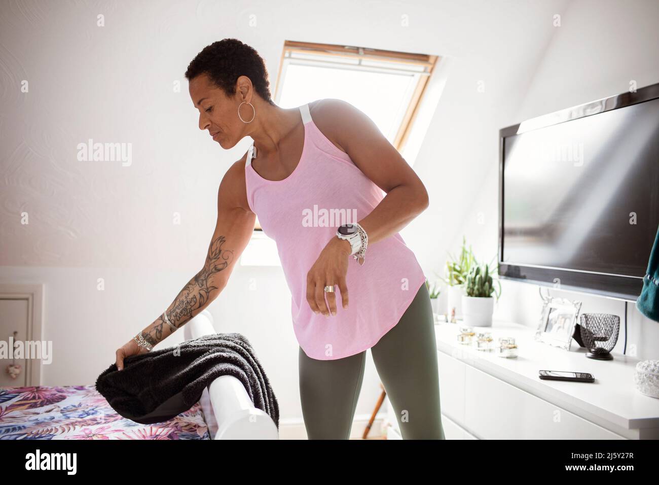 Reife Frau mit Tattoos, die sich im Schlafzimmer anzieht Stockfoto