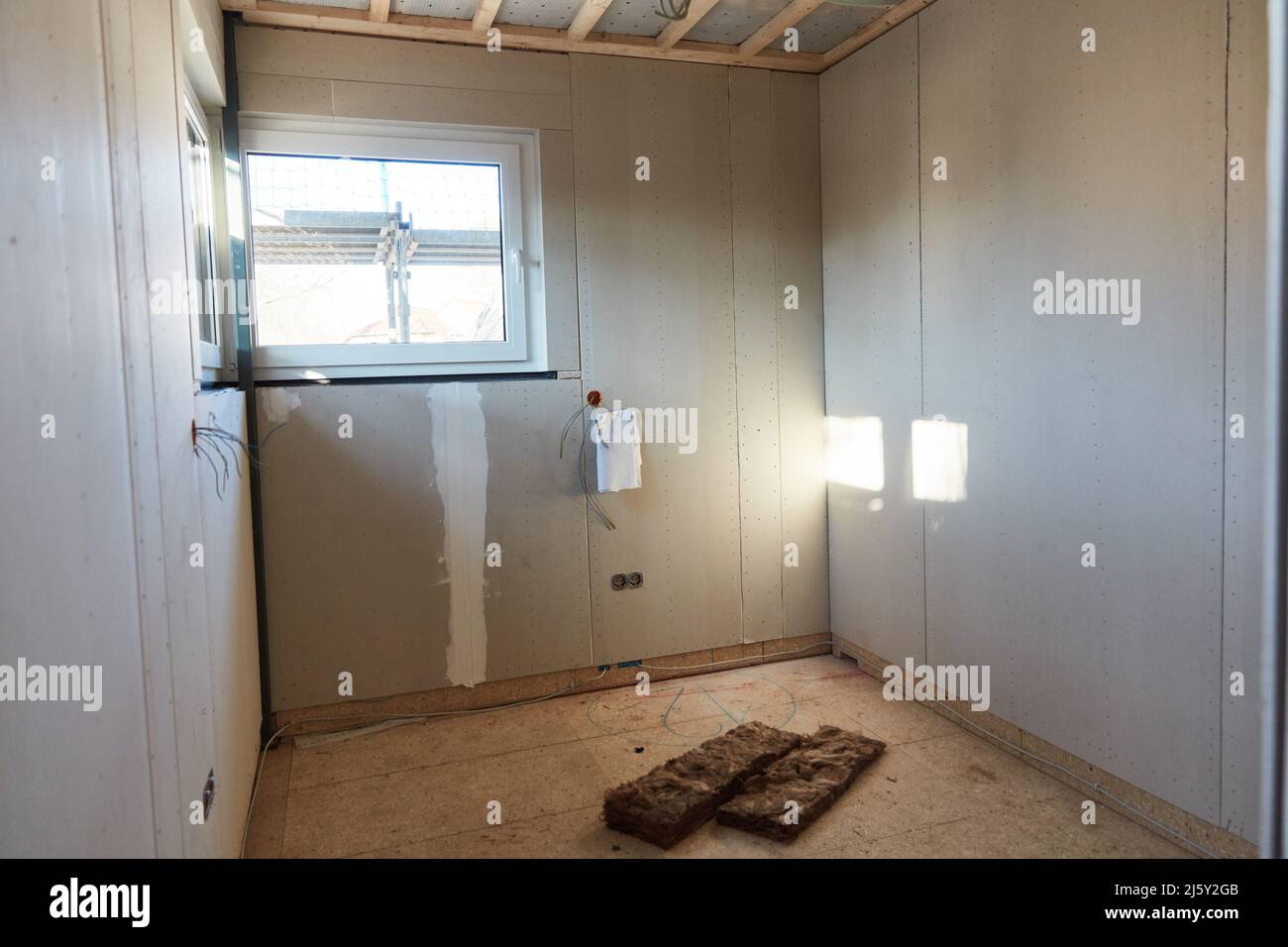 Zimmer im neuen Gebäude mit Eckfenster und isolierender Wolle auf dem Boden Stockfoto