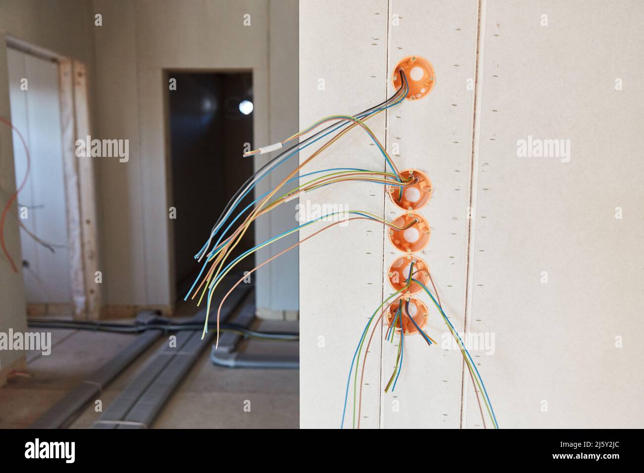 Elektroinstallation für viele Lichtschalter im Neubau mit losen Stromkabeln Stockfoto