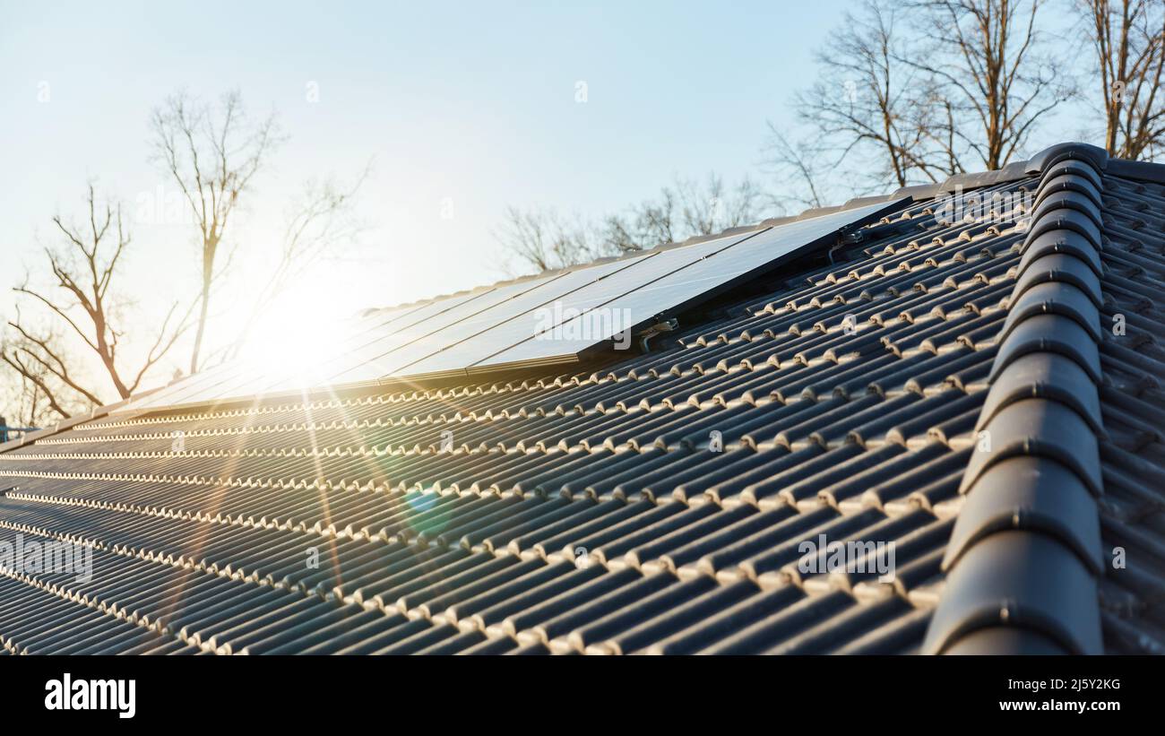 Die Sonne scheint auf moderne Solaranlage auf dem Hausdach als erneuerbare Energie Stockfoto