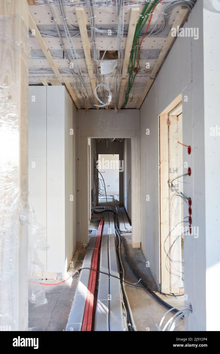 Korridor oder Korridor als Baustelle für den Hausbau im Neubau mit Kabeln und Rohren Stockfoto