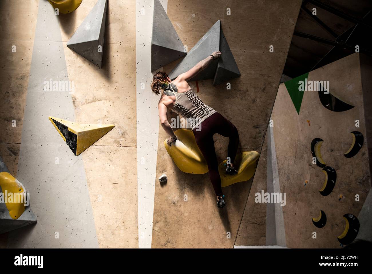 Junge Frau, die die Kletterwand erklimmen Stockfoto