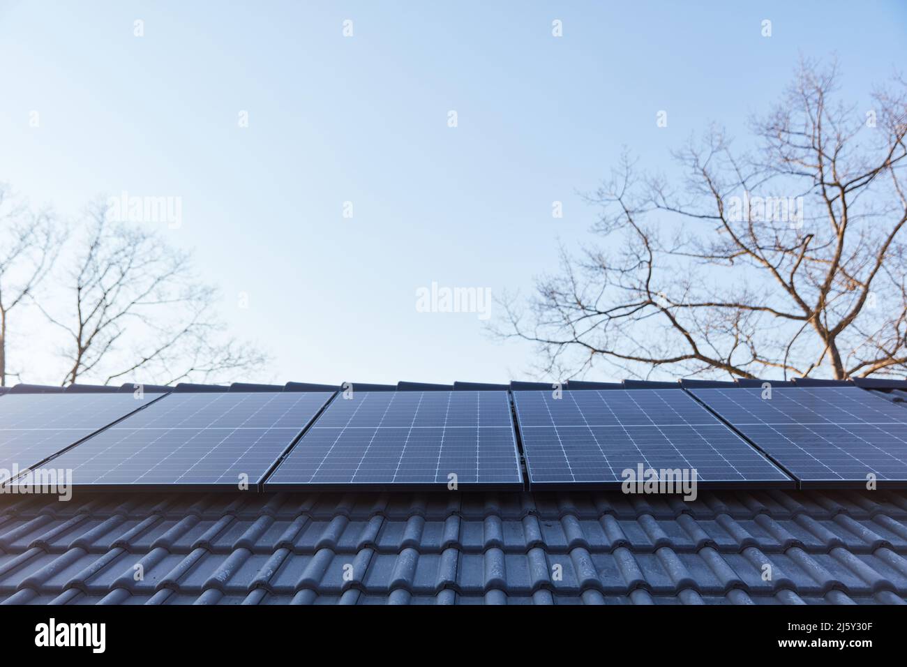Neue Sonnenkollektoren für Sonnenenergie auf dem Dach eines Hauses gegen den blauen Himmel Stockfoto