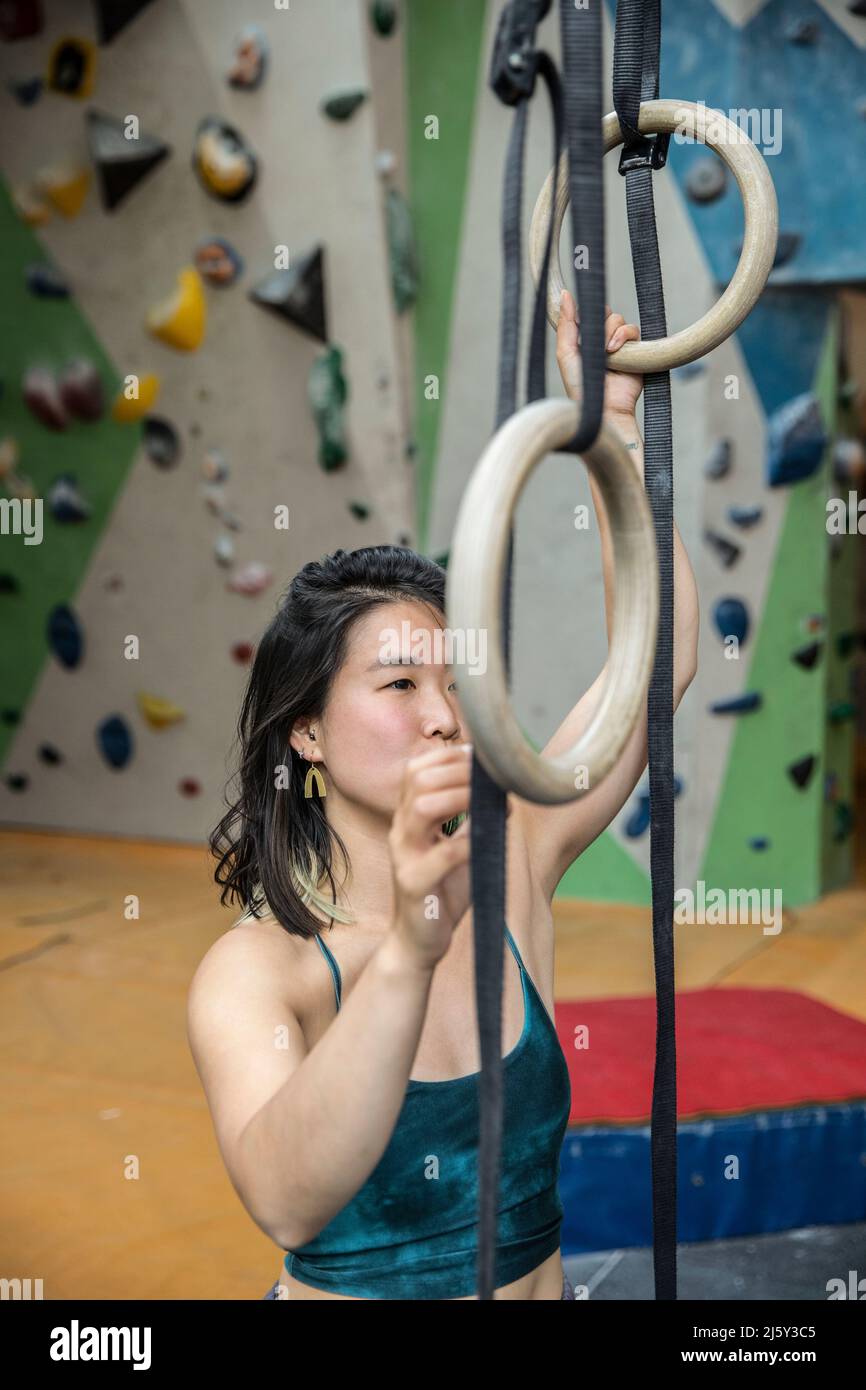 Frau, die an Turnringen im Kletterzentrum trainiert Stockfoto