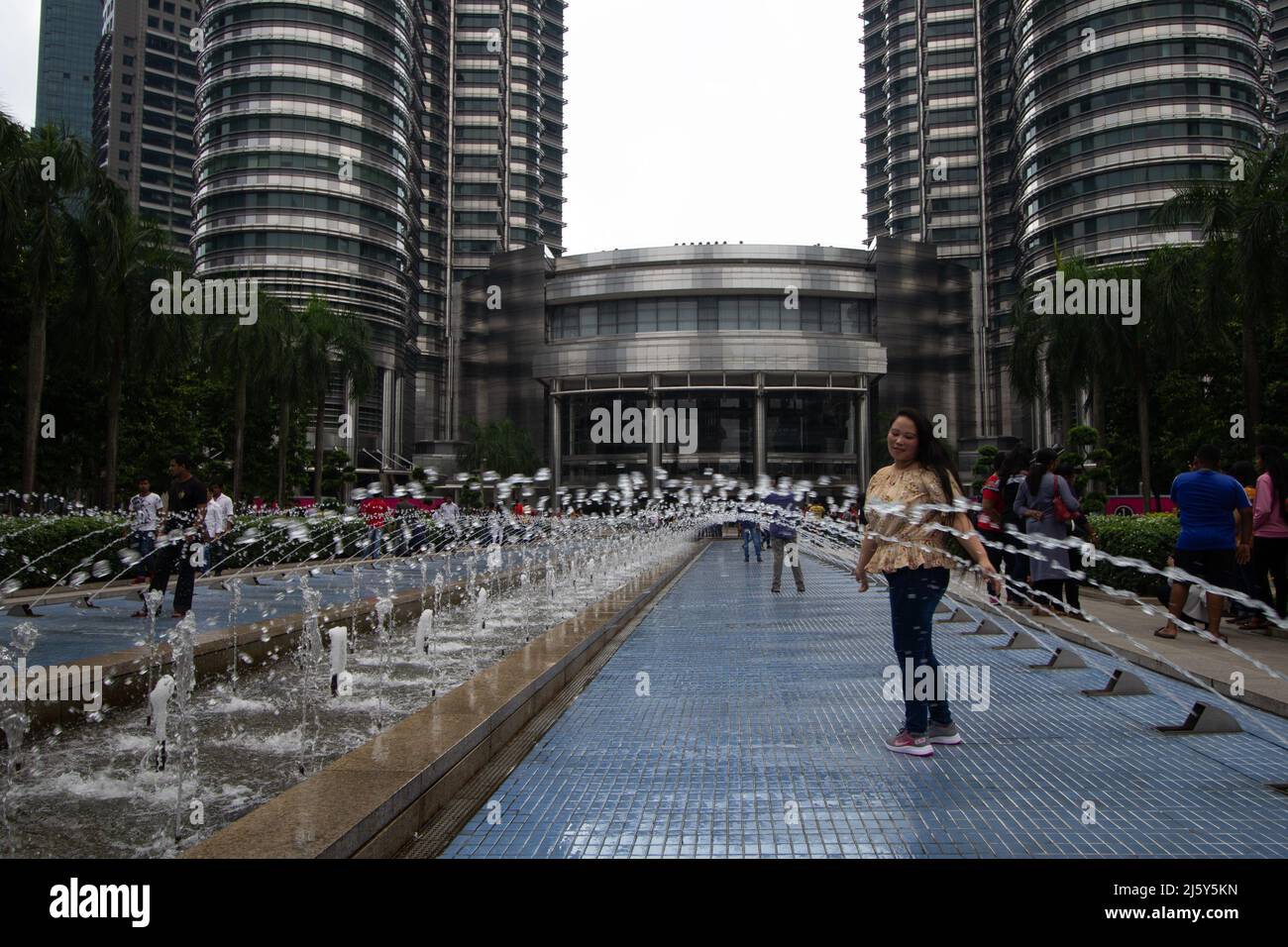 KUALA LUMPUR, MALASIA – 26. JANUAR 2020 Menschen spielen in den Wasserfontänen am Fuße der Petronas Twin Towers Stockfoto