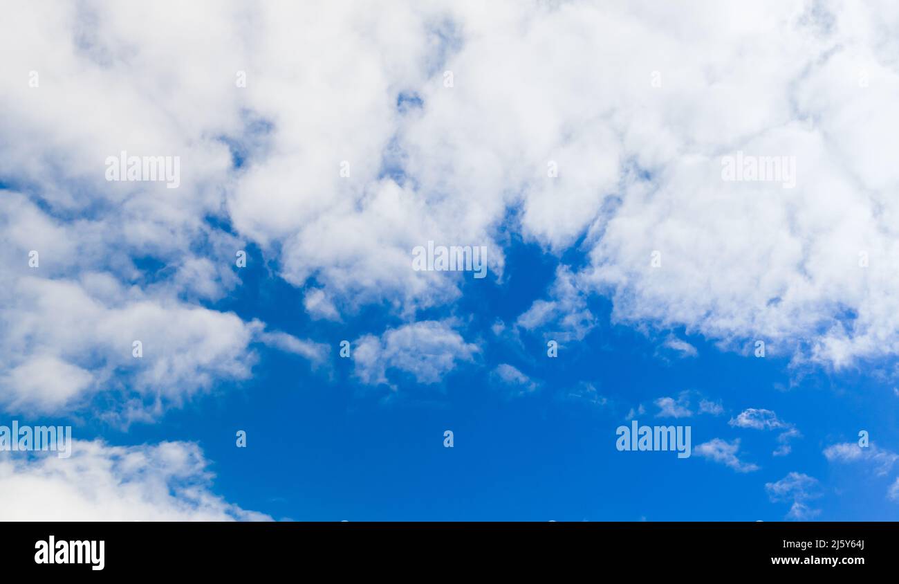 Blauer Himmel mit weißen Wolken. Cumulus und Altocumulus Arten von Wolken. Natürliches Hintergrundfoto Stockfoto