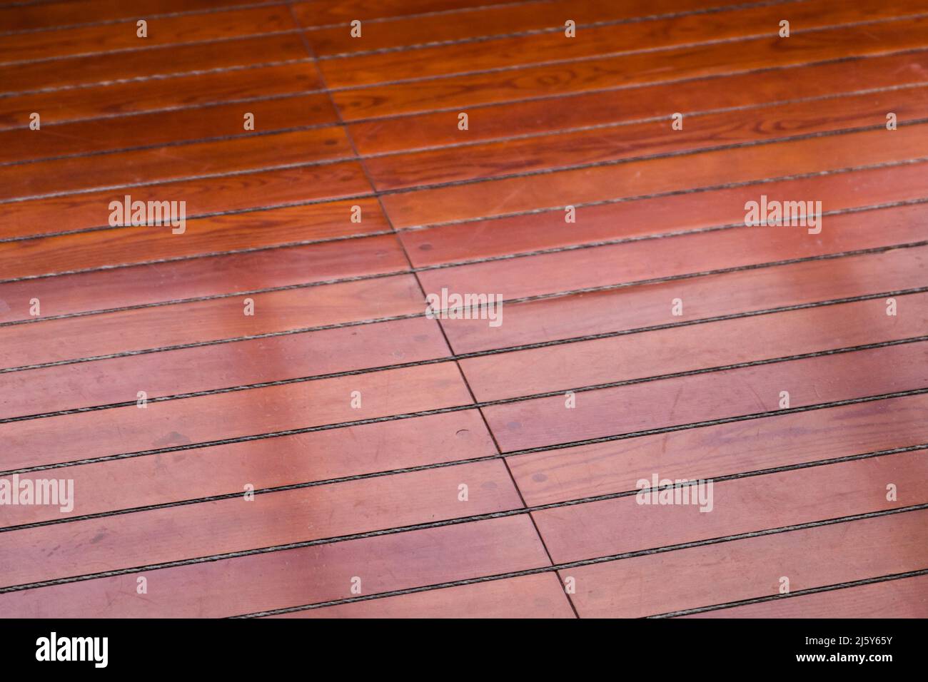 Glänzendes Yachtdeck aus roten Holzplanken, Nahaufnahme Stockfoto