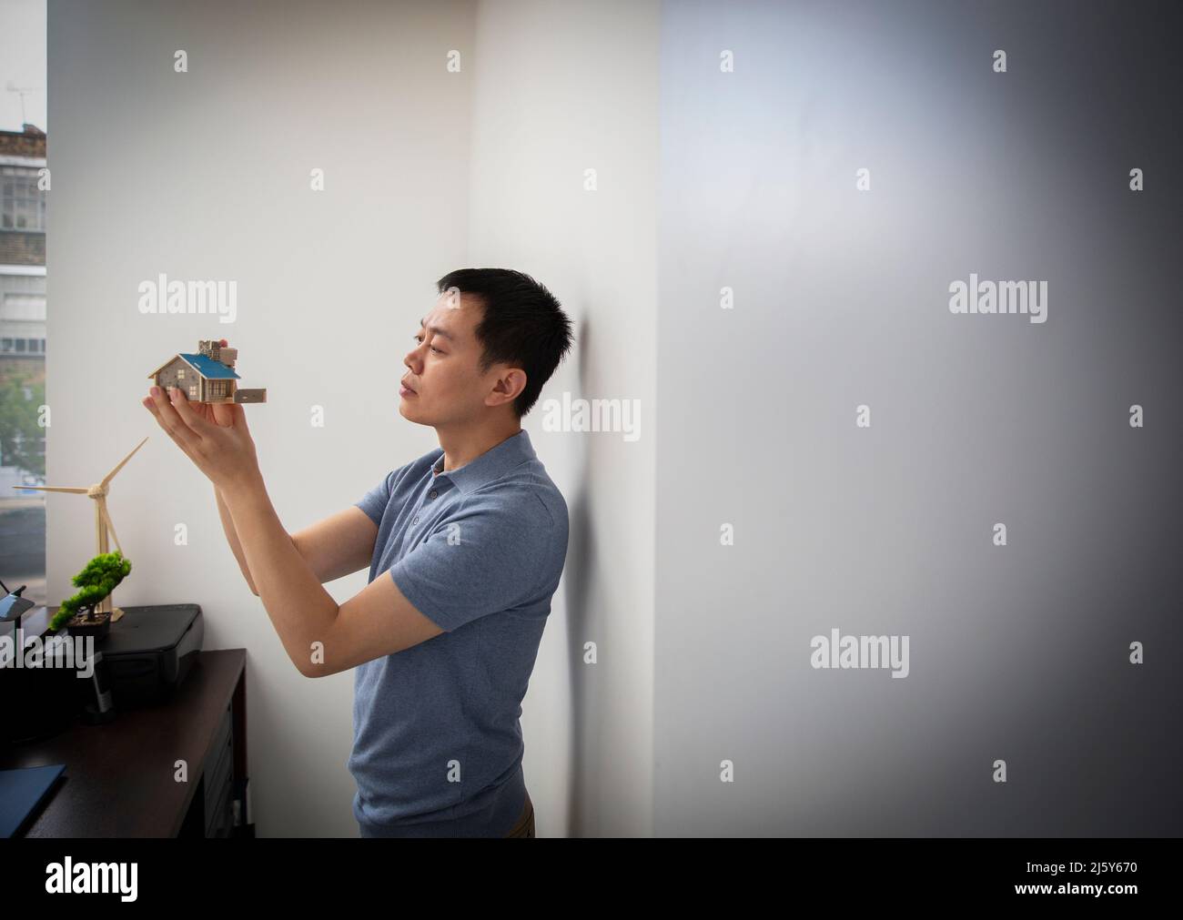 Männlicher Architekt, der das Hausmodell im Büro inspiziert Stockfoto