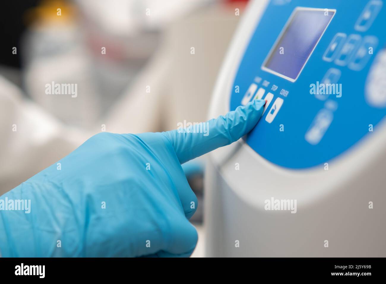 Nahaufnahme Labormitarbeiter Hand in Gummihandschuhe legt Parameter auf der Zentrifuge für die Probenvorbereitung fest. DNA, onkologische Markeranalyse im klinischen Labor. Stockfoto