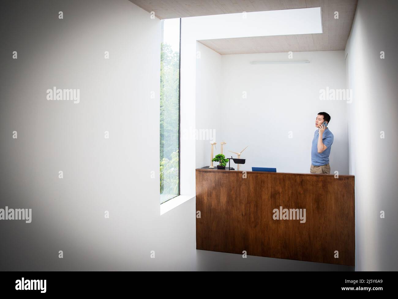 Männlicher Ingenieur, der hinter dem Schreibtisch im Büro auf dem Smartphone spricht Stockfoto