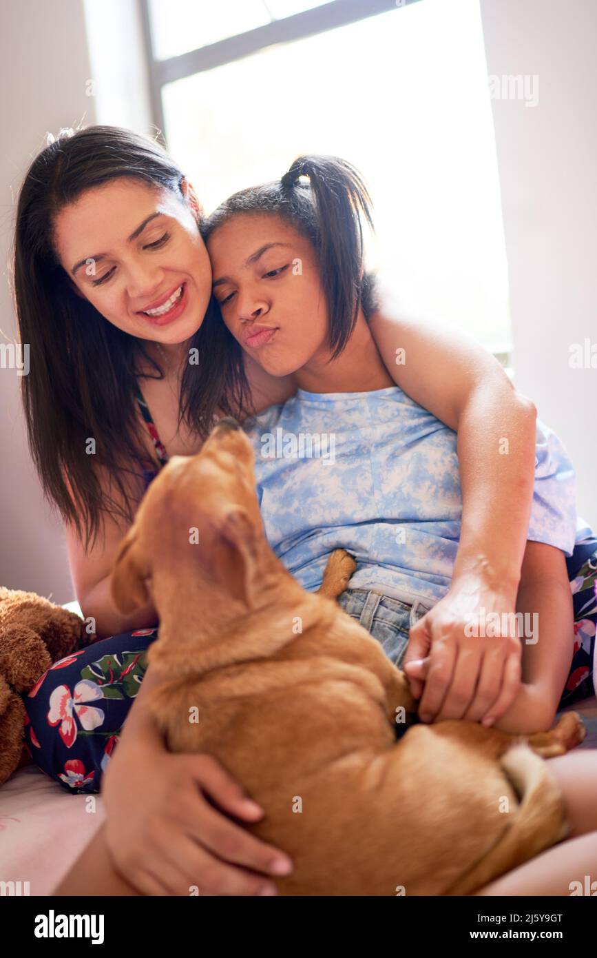 Lächelnde Mutter und behinderte Tochter mit niedlichem kleinen Hund Stockfoto