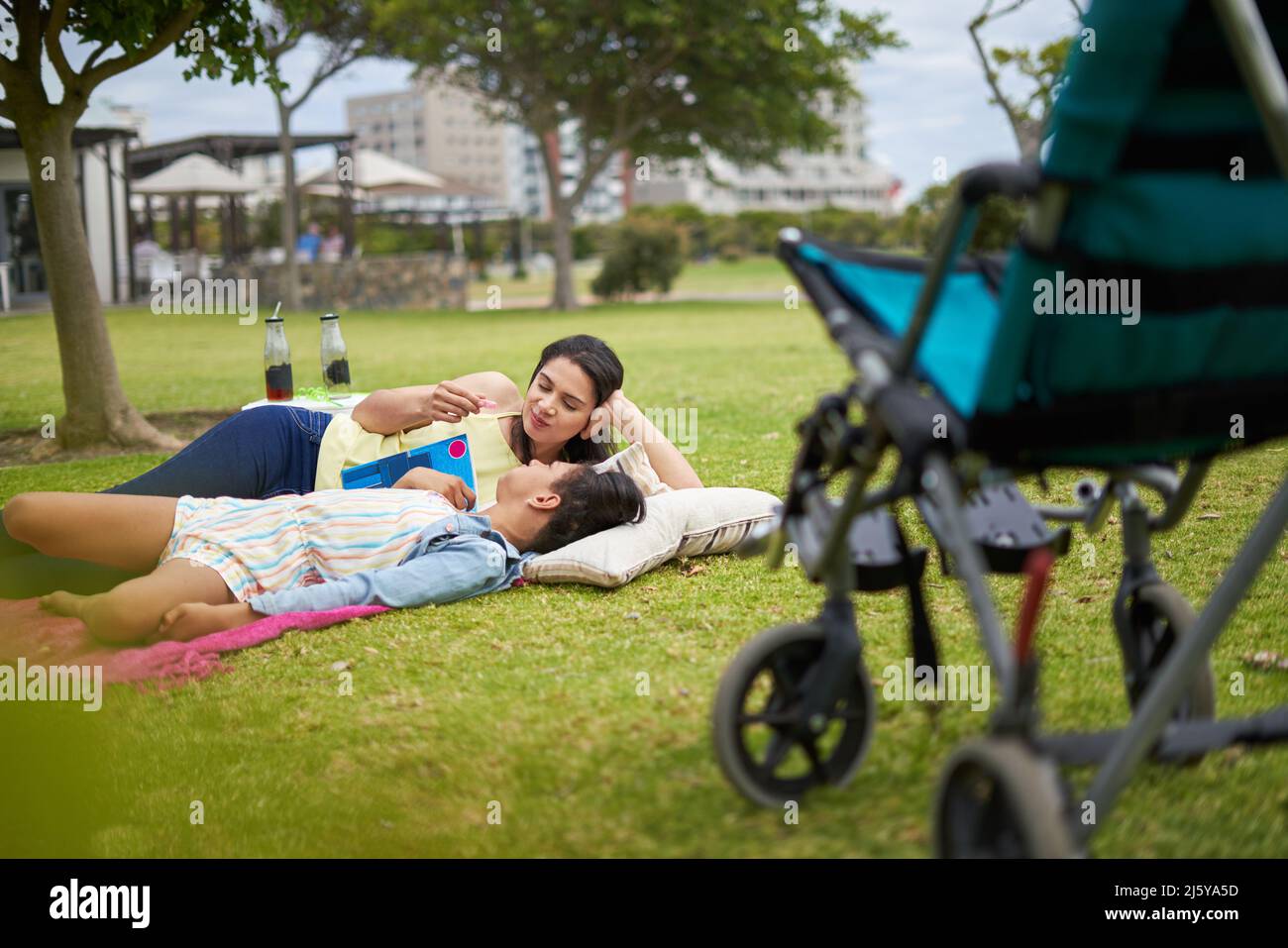 Mutter und behinderte Tochter liegen und reden im Park Stockfoto