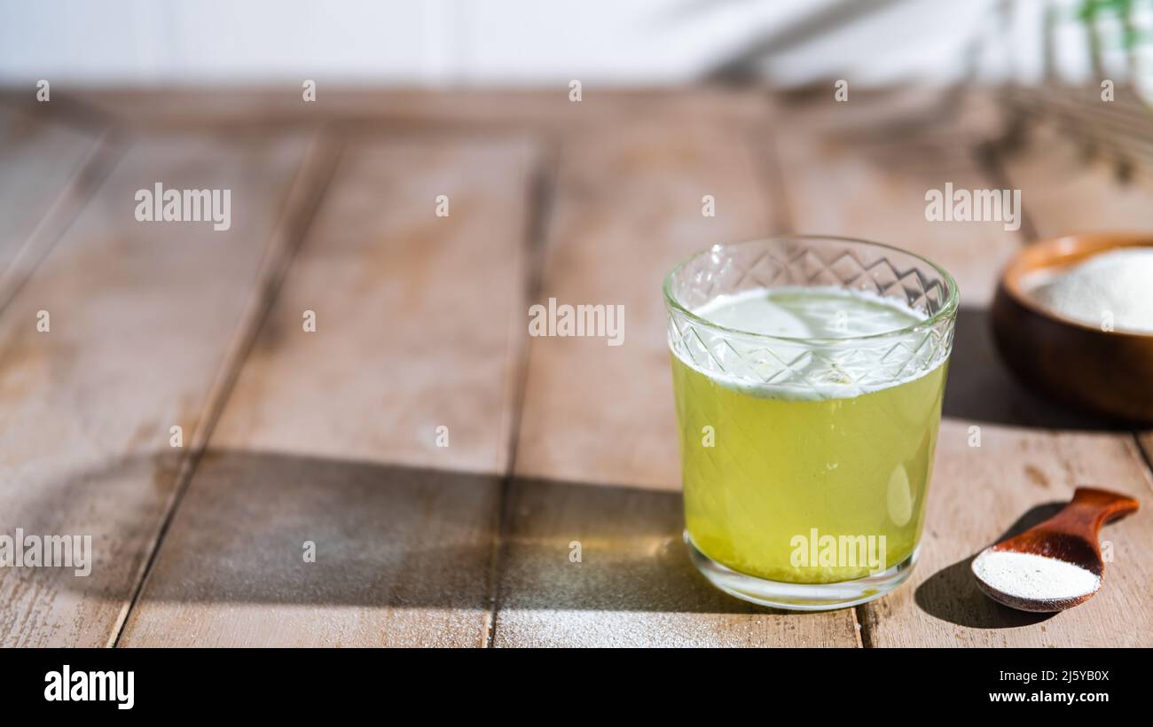 Kollagenpulver und Glas Wasser auf Holzgrund. Zusätzliche Proteinaufnahme. Natürliche Schönheit und Gesundheit zu ergänzen Stockfoto