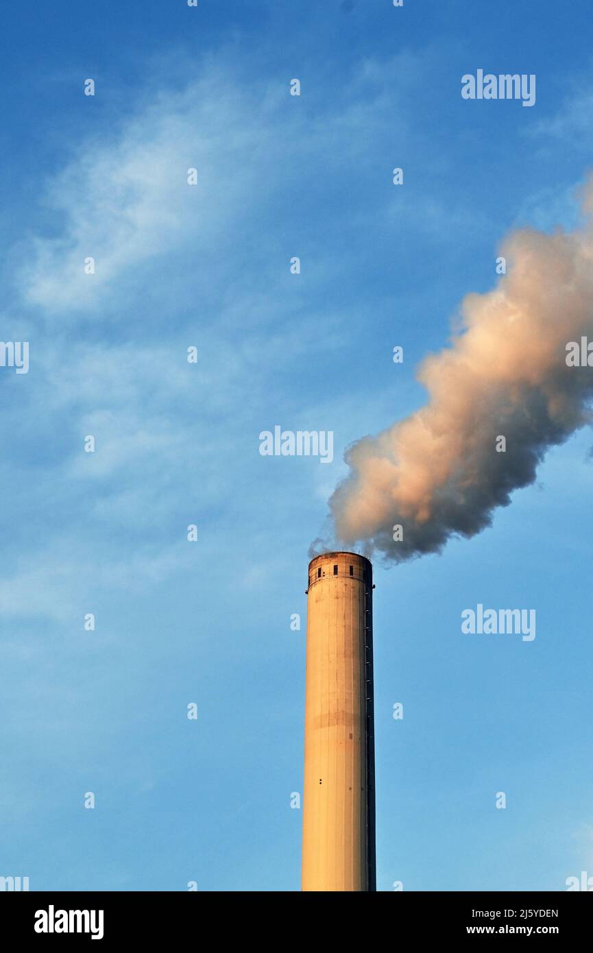 Rauch, der in der Dämmerung das große Glockenspiel eines Kraftwerks ausblendet, das vor einem blauen Himmel isoliert ist. Keine Personen. Speicherplatz kopieren. Stockfoto