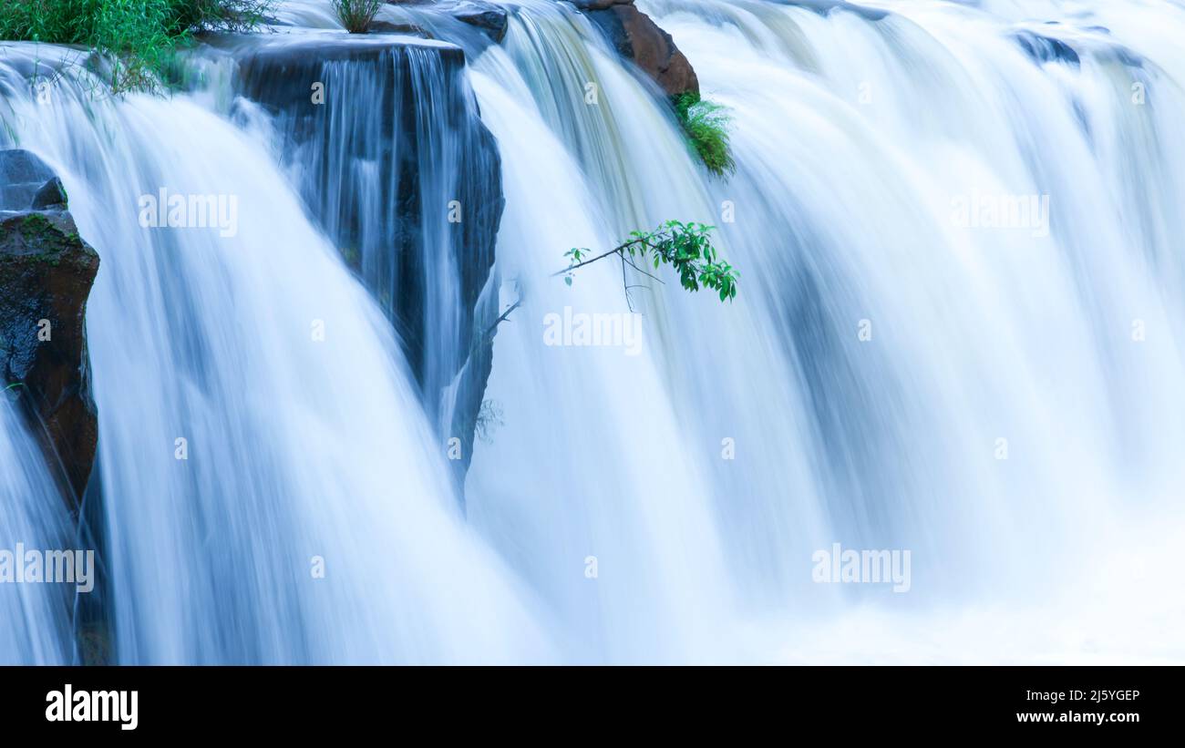 Die Landschaft des TAD Pha Suam Wasserfalls in der Regenzeit, Süßwasser fließt aus dem Felsvorsprung, Reiseziele in Süd-Laos. Stockfoto