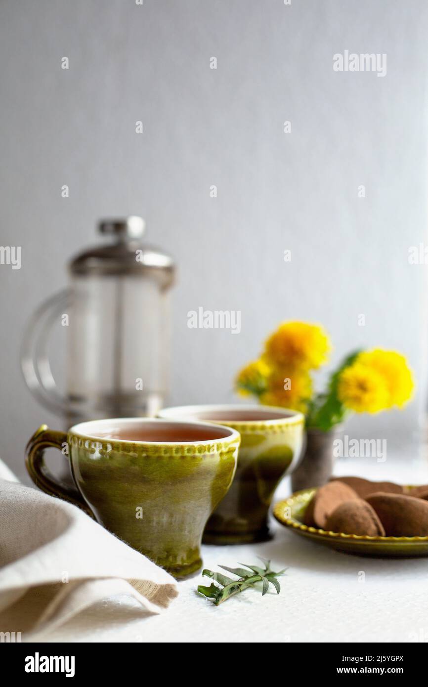 Frühlingsstill-Leben mit Tee, Süßigkeiten und Dandelionen Stockfoto