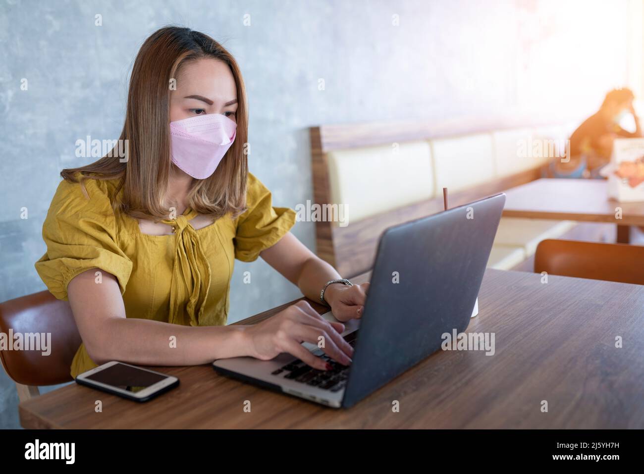 Geschäftsfrau trägt Maske verwenden Laptop arbeiten im Café Stockfoto