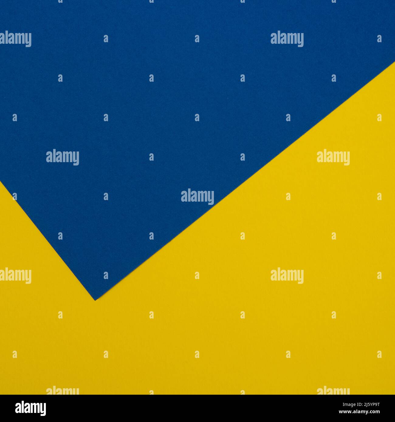 Zwei Blätter aus gelbem und blauem Papier überlappend als Hintergrund angeordnet Stockfoto