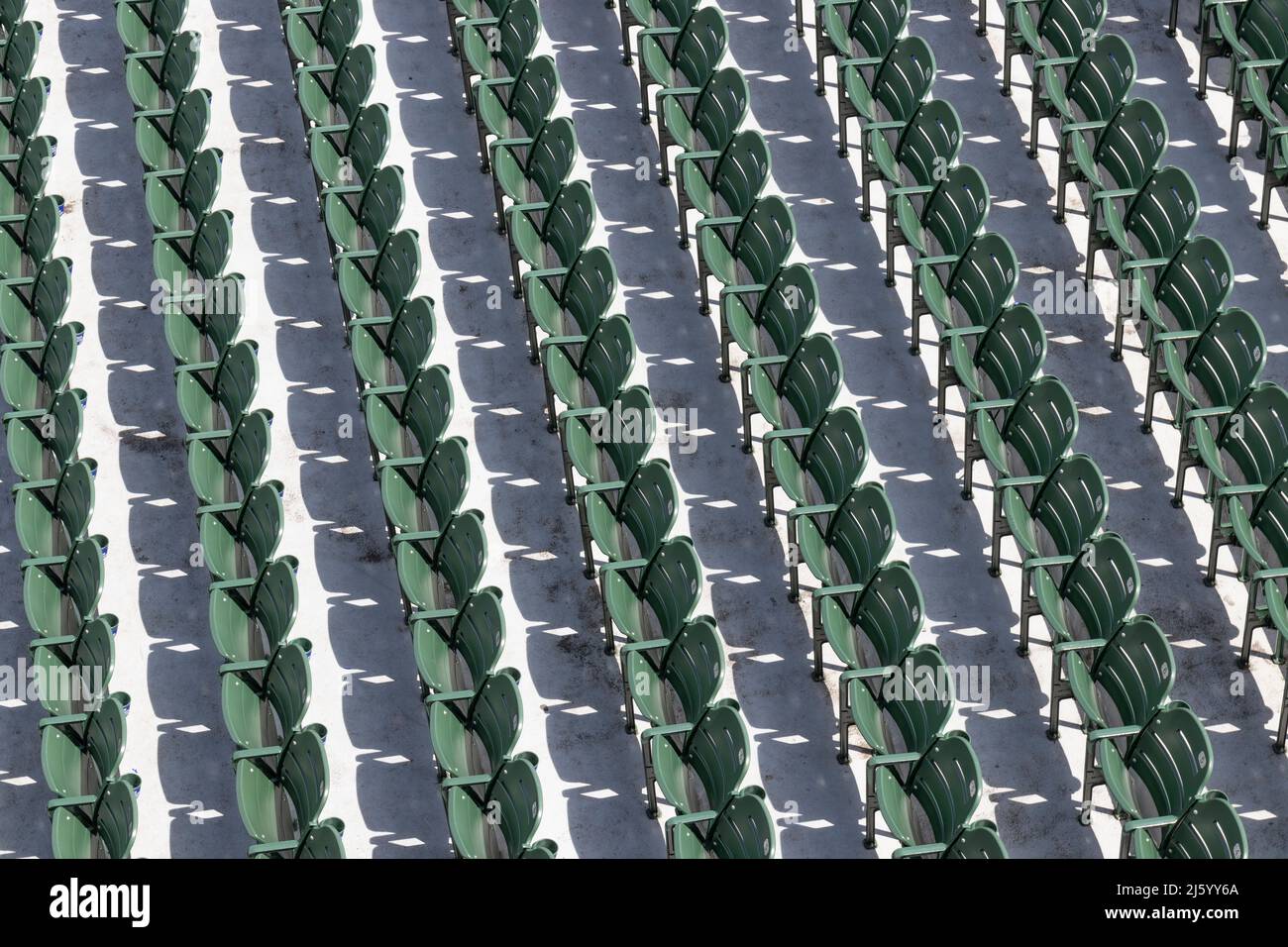 Reihen von leeren grünen Sitzen bei einer Sportveranstaltung im Freien an einem sonnigen Tag. Stockfoto