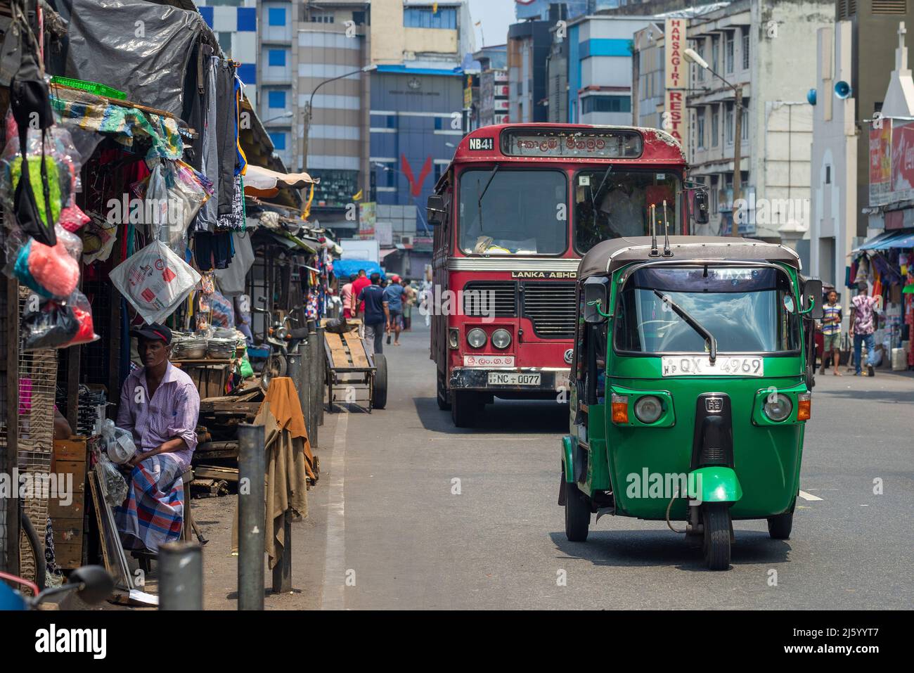 COLOMBO, SRI LANKA - 23. FEBRUAR 2020: Tuk Tuk und Stadtbus fahren am Straßenmarkt vorbei Stockfoto